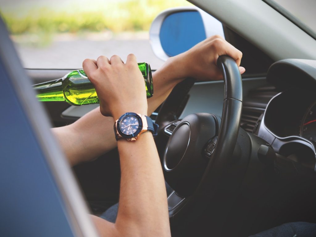 someone driving while drinking a beer bottle 