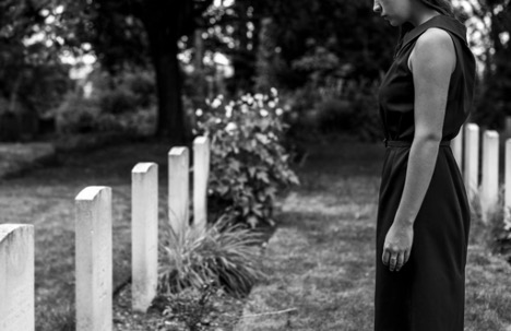 Woman mourning beside gravestones in cemetery