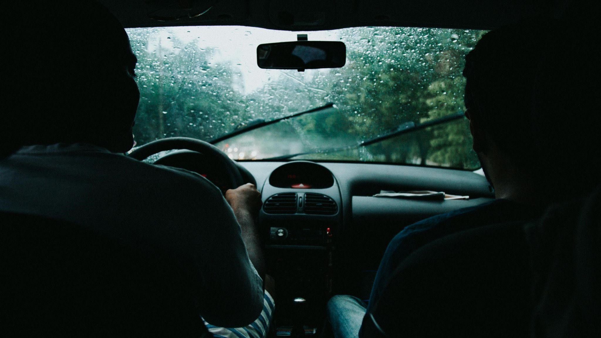 two people in a car driving in a rainy day