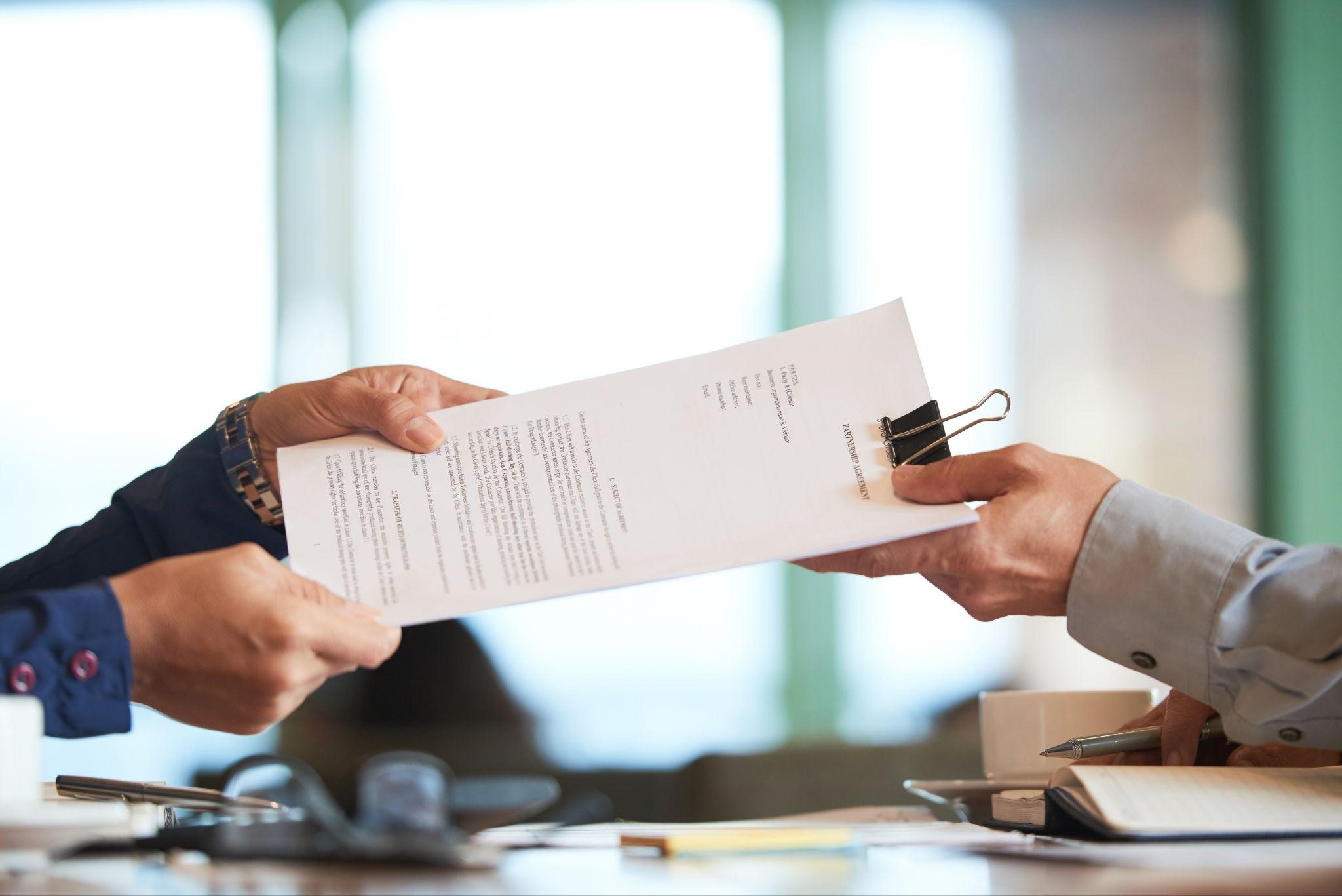 two people handing each other a document