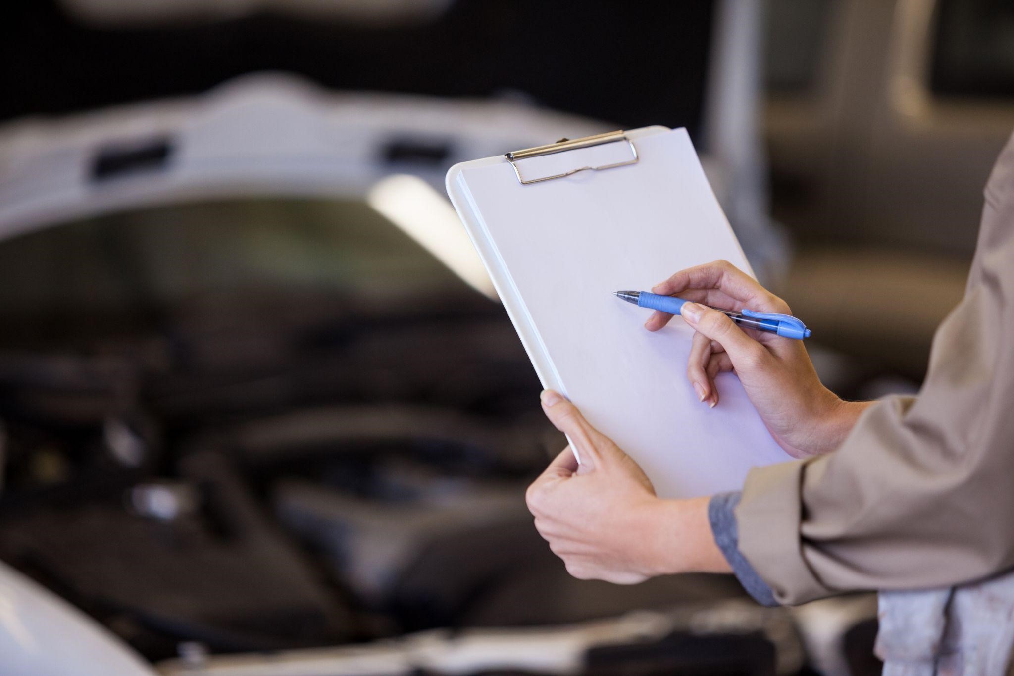 person holding a checklist in front of a car